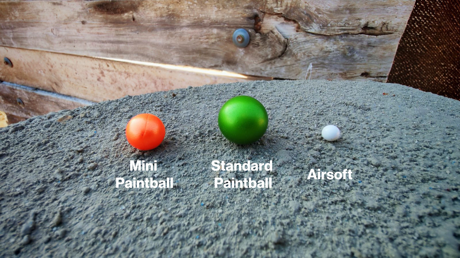 Side-by-side size comparison of a paintball, mini paintball, and airsoft BB
